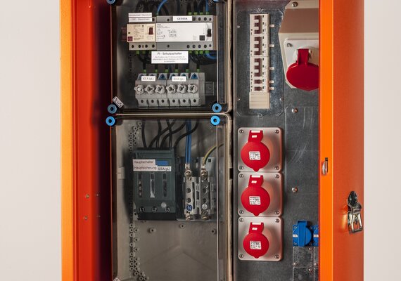 Ein Baustromverteiler der Marke metall-Meister mit der Körperfarbe Orange und drei Steckdosen 