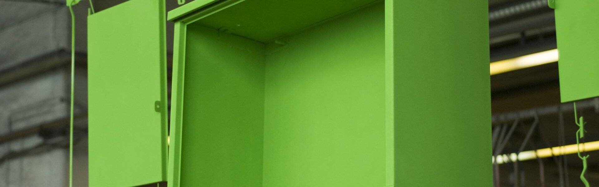 das grün lackierte Schubladenschrankgehäuse kommt aus der Pulverbeschichtungsanlege heraus und wird zu Trockenen vorbereitet 